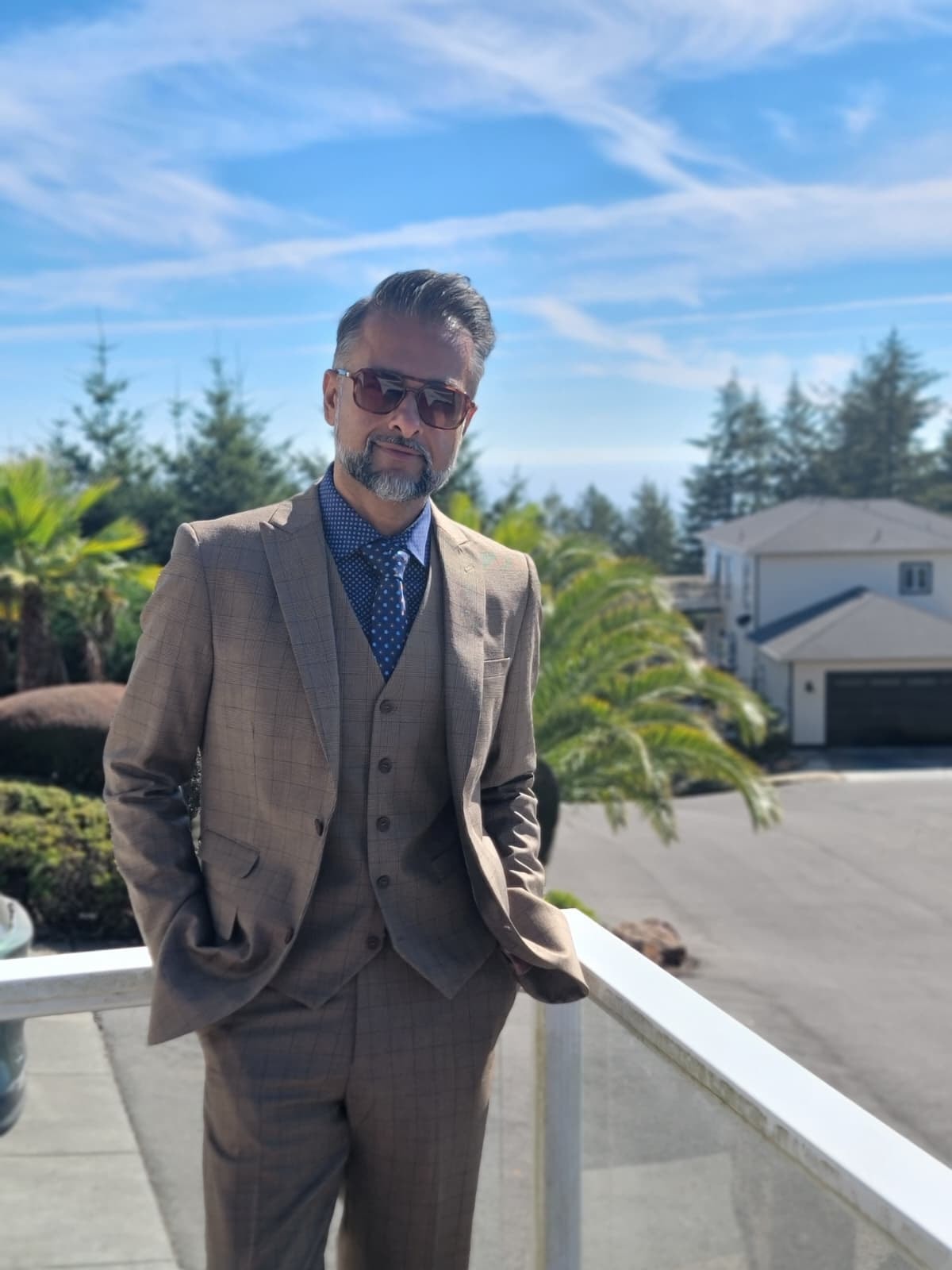 The Toofan — putting on a blue overshirt on a deck railing overlooking the Pacific Northwest ocean