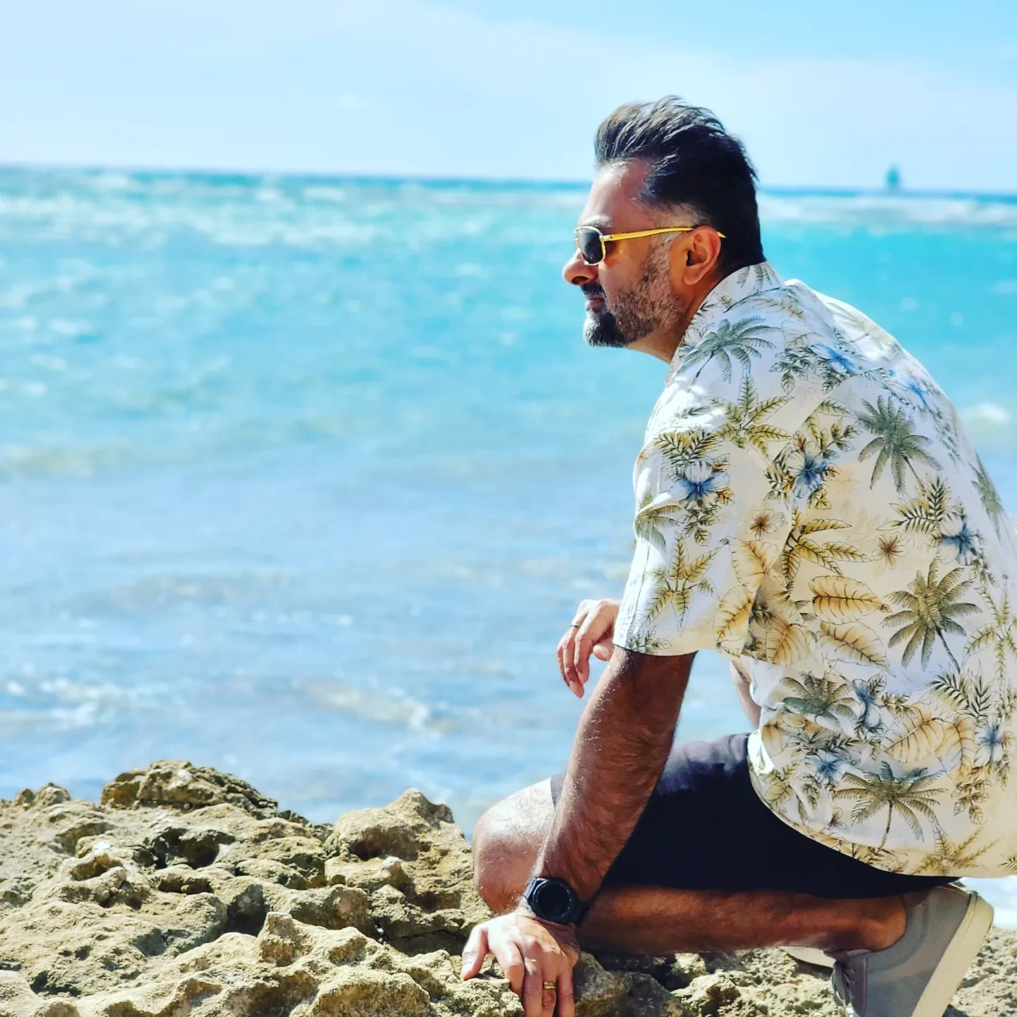 The Toofan — blue overshirt and sunglasses on a balcony with ocean view